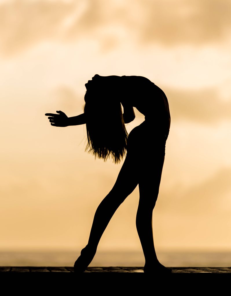 Silhouette of gymnast performing backbend at golden sunset showcasing strength and grace Wallpaper