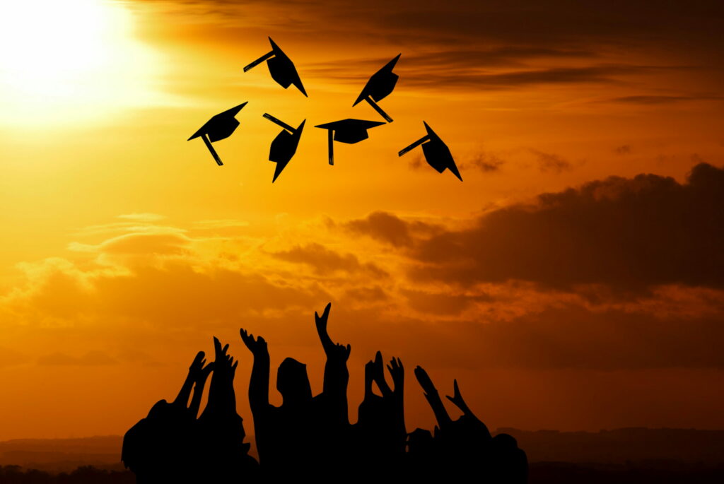 Silhouette of graduates tossing mortarboards at golden sunset inspiring graduation celebration wallpaper