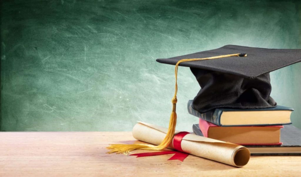 Graduation cap diploma on books with green chalkboard background symbolizing academic success Wallpaper