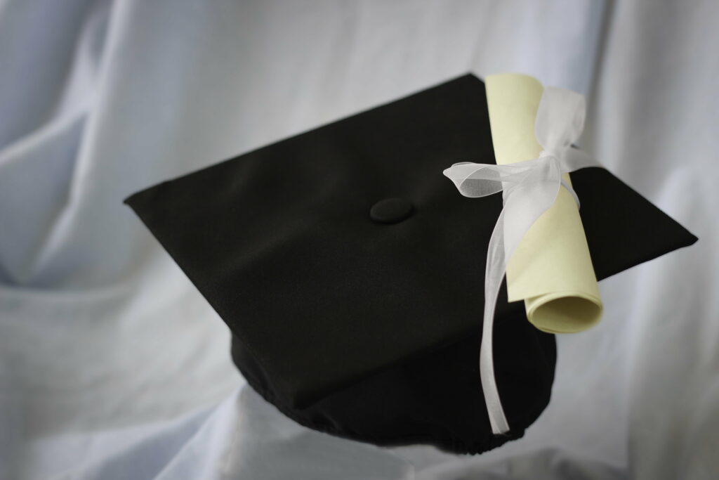 Elegant graduation wallpaper with black mortarboard cap diploma on soft white fabric background