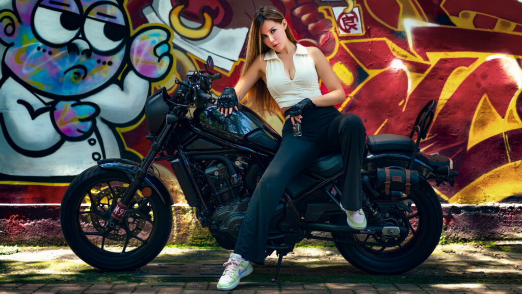 Graffiti Chic: Stylish Girl Model Poses on Bike in White Top and Jeans Wallpaper