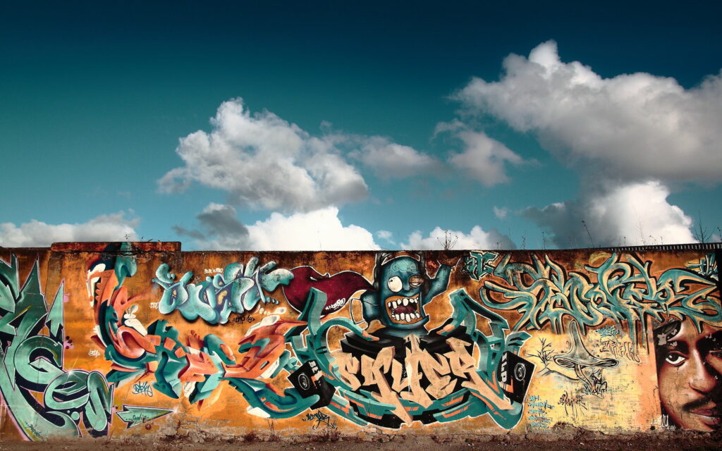 Bursting with Vibrant Street Art: Captivating Wall Mural Painted Against a Dramatic Sky - HD Graffiti Wallpaper