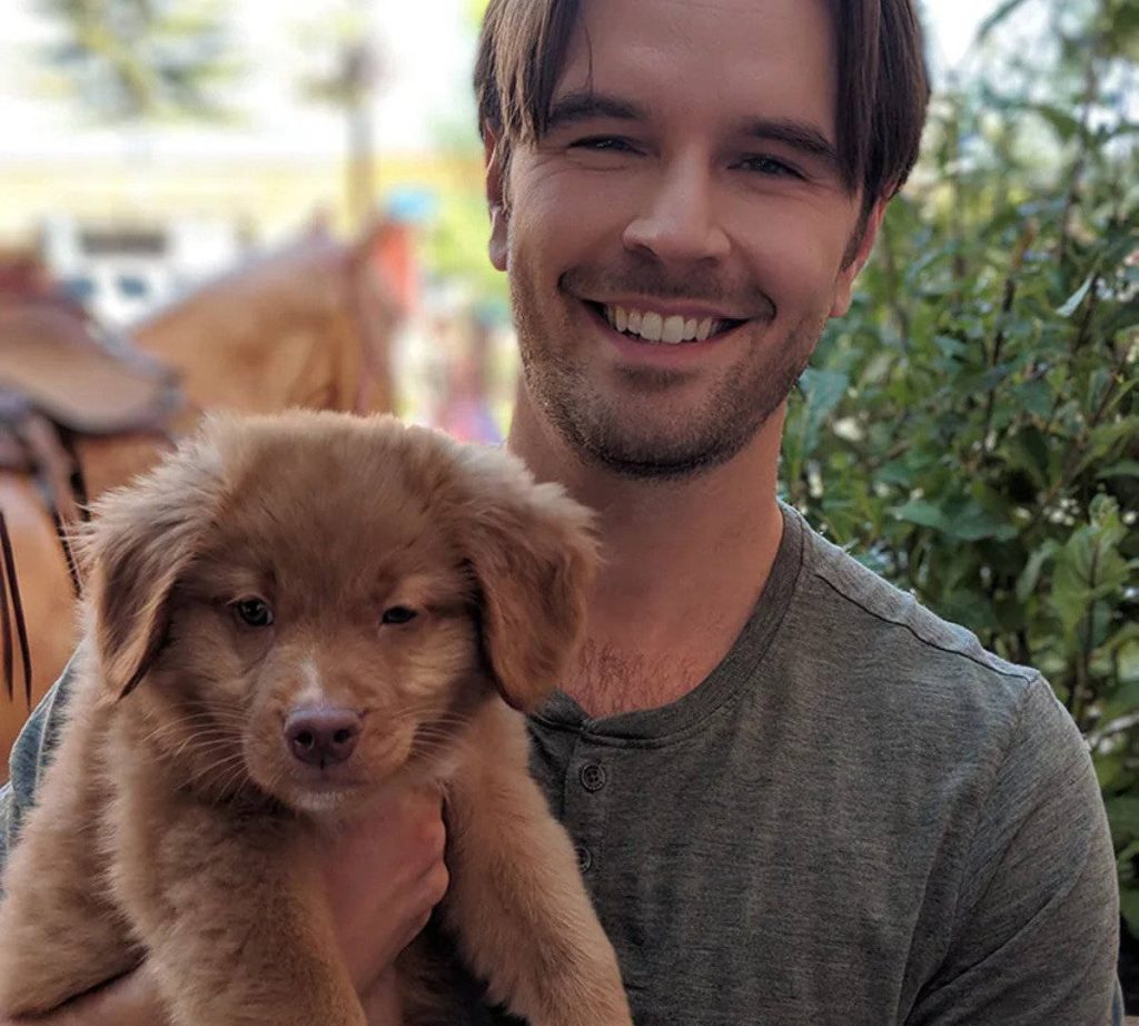 Graham Wardle smiling holding fluffy brown puppy outdoors bright natural light ranch wallpaper