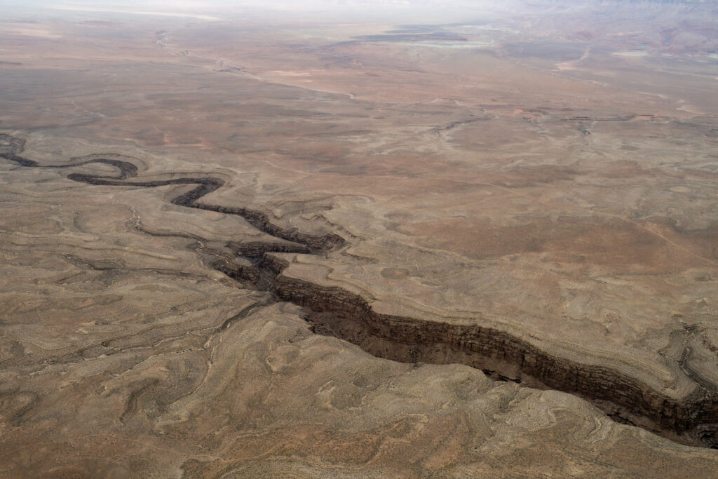 Aerial view of Grand Canyon showcasing rugged relief winding canyon crevice and desert tones Wallpaper