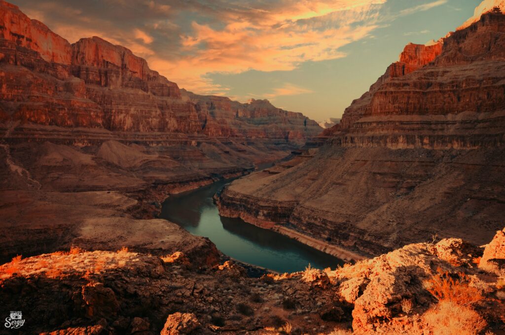 Grand Canyon sunset landscape with rocky cliffs and winding river reflecting warm sky hues wallpaper