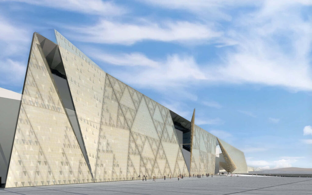 Grand Egyptian Museum exterior with angular beige facade under bright blue sky and soft clouds Wallpaper