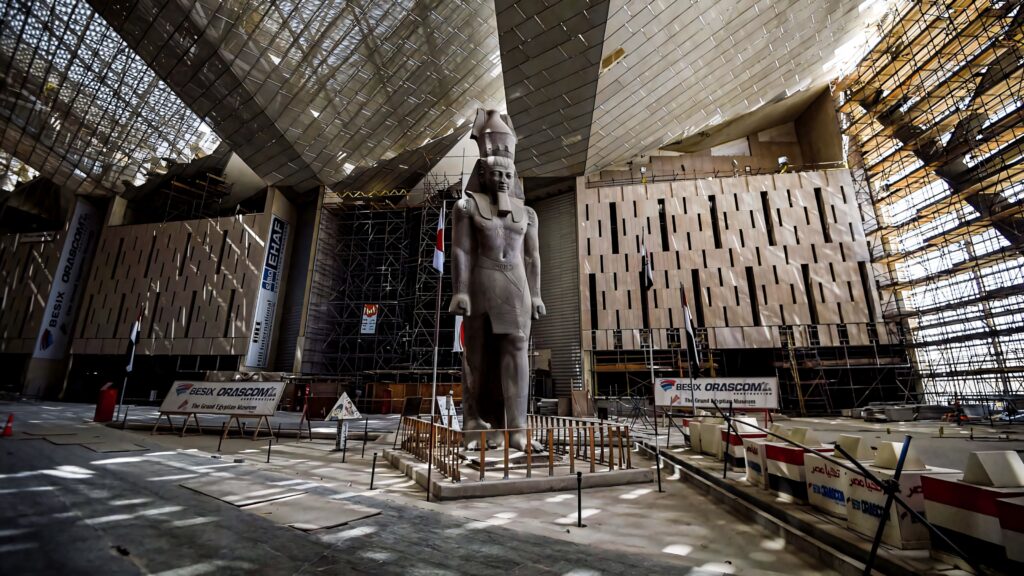 Grand Egyptian Museum interior with towering statues geometric patterns warm light modern design Wallpaper