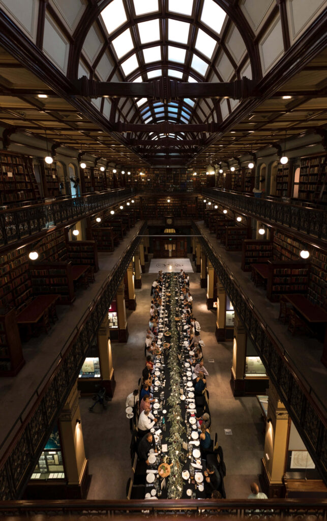 Grand gala dinner at Adelaide State Library with elegant table under arched ceiling and bookshelves Wallpaper