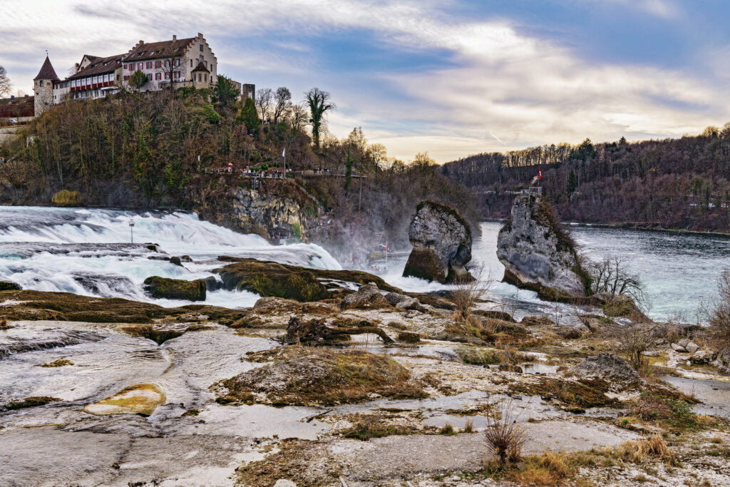 Grand house on hill by waterfall river surrounded by trees rocks under dramatic sky wallpaper background