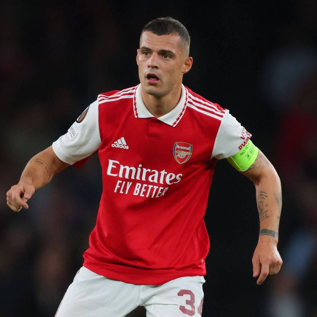 Granit Xhaka in Arsenal red white captain kit action shot stadium background wallpaper