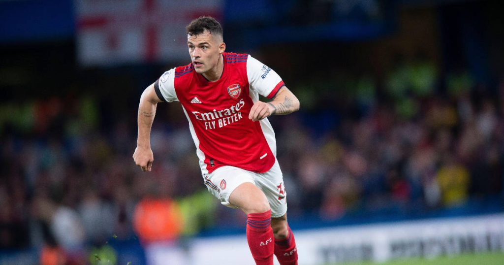 Granit Xhaka running in red Arsenal kit dynamic football action stadium background wallpaper