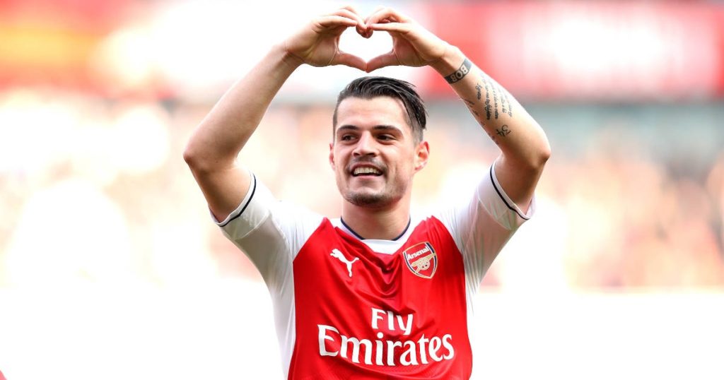 Granit Xhaka smiling in red white Arsenal jersey heart hand pose vibrant sports wallpaper background