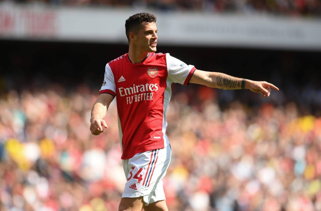 Granit Xhaka in Arsenal red white kit gesturing on sunlit pitch stadium background wallpaper