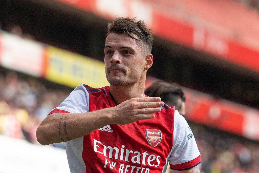 Granit Xhaka Arsenal midfielder celebrating with hand gesture in red white kit stadium background Wallpaper