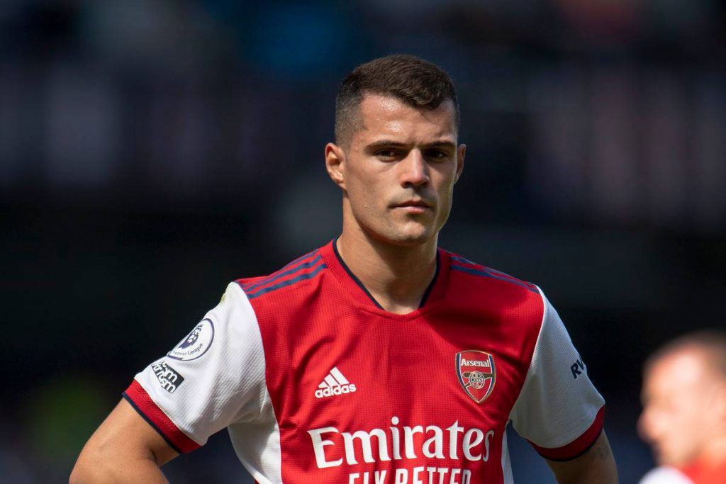 Granit Xhaka focused in Arsenal red and white kit showing determination on football pitch wallpaper