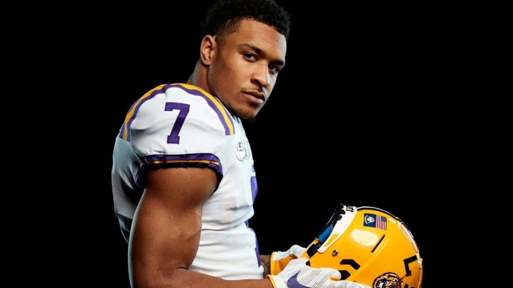 Grant Delpit LSU Tigers white jersey number 7 holding gold helmet dramatic lighting wallpaper