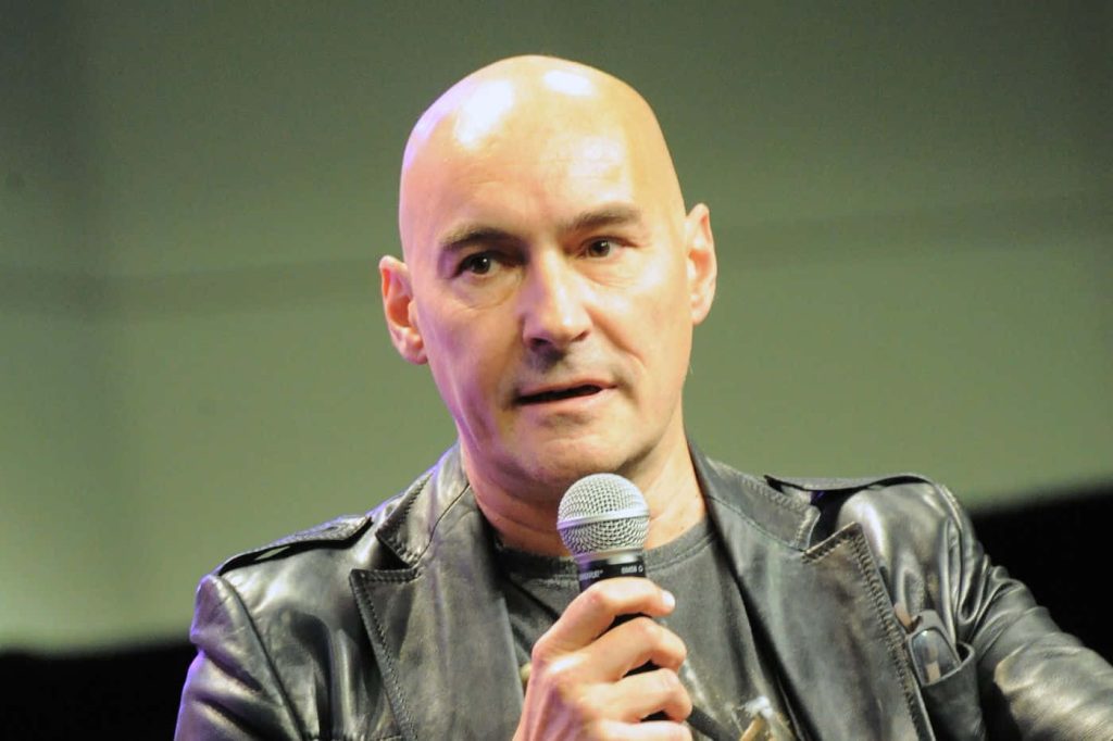 Grant Morrison comic book writer in black leather jacket speaking into microphone portrait wallpaper