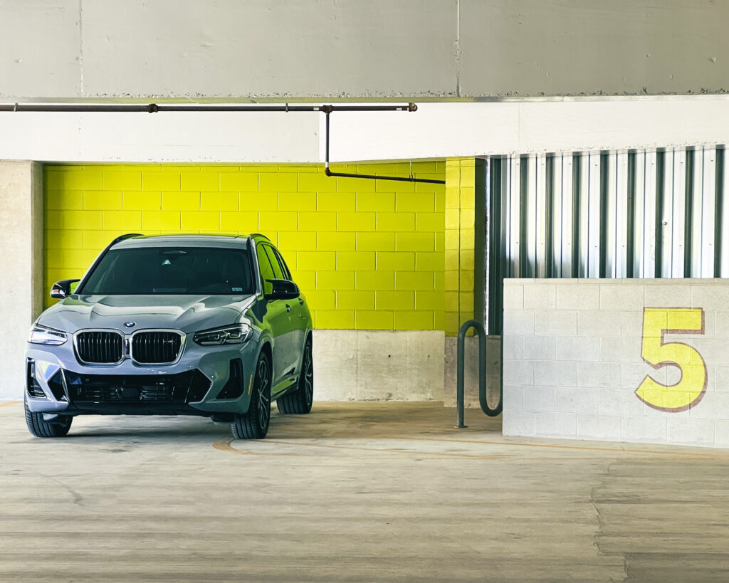 Gray BMW X7 in Industrial Setting with Vibrant Green Walls Wallpaper