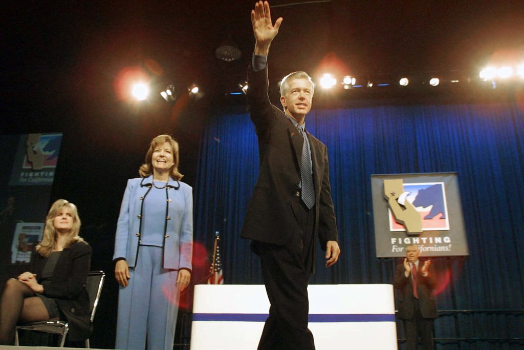 Gray Davis waving with Sharon Davis at California campaign rally bright blue stage background Wallpaper