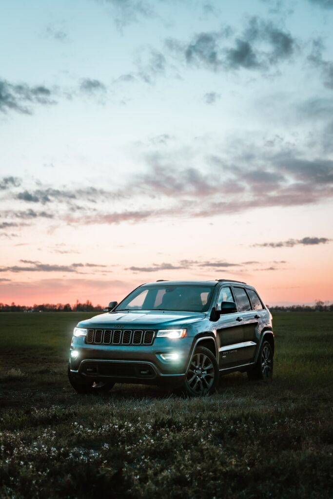 Twilight Serenity: Gray Jeep Grand Cherokee in Orange-Pink Sky Wallpaper