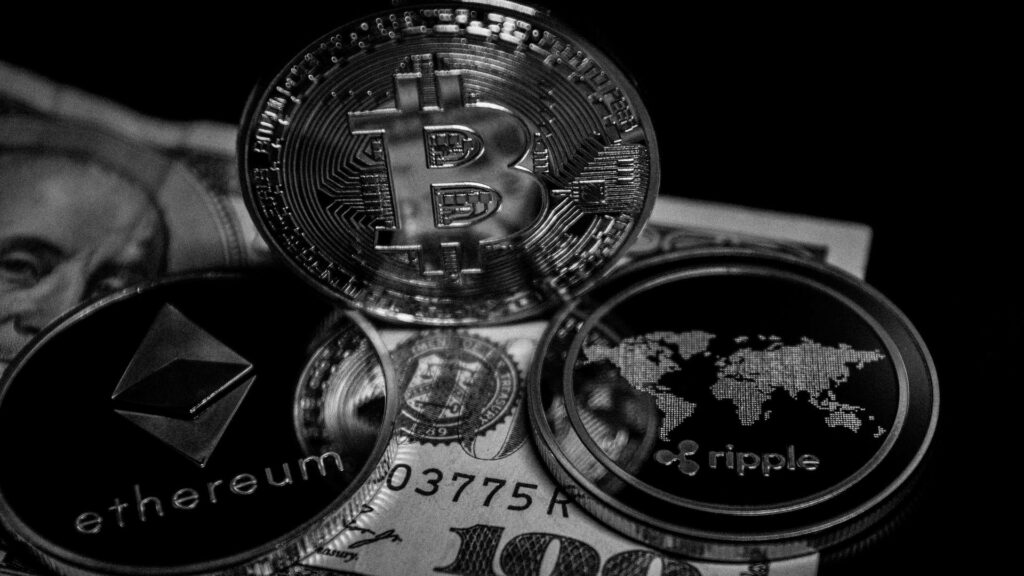 Grayscale wallpaper of Ethereum Bitcoin Ripple coins on US dollar highlighting digital crypto theme