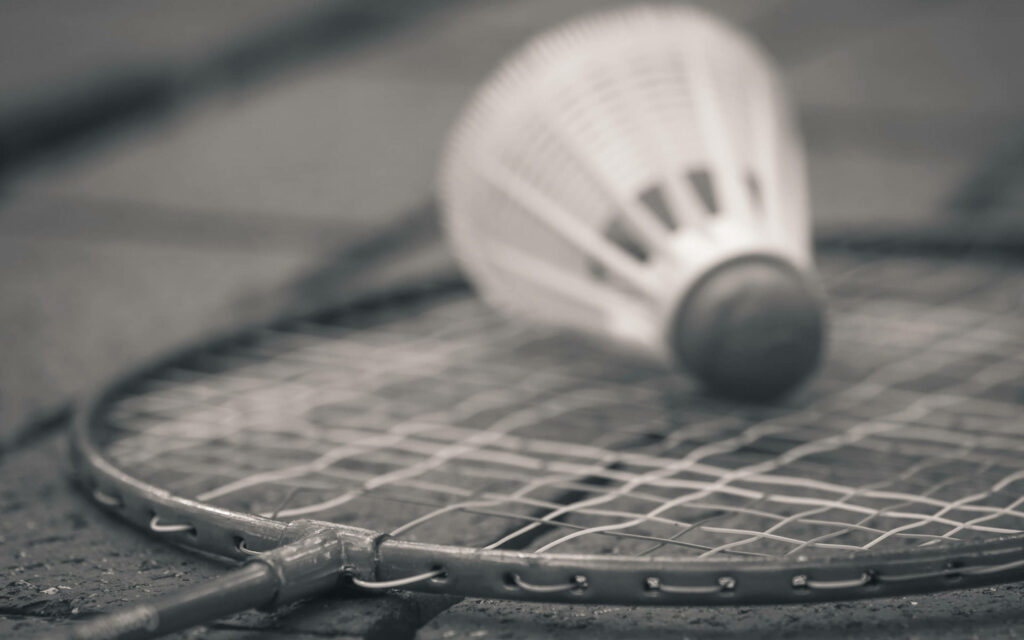 Up-close View of a Badminton Racket and Shuttlecock on Concrete Bricks Dynamic Detail: Black and White Close-up Image of a Badminton Racquet Head with Shuttlecock on Concrete Background Fierce Focus: Macro Shot of Badminton Racket and Shuttlecock against Grayscale Concrete Bricks Wallpaper