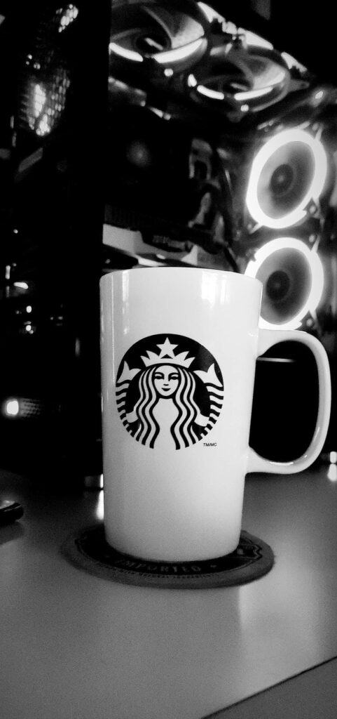 Grayscale Starbucks coffee mug with modern illuminated computer setup tech wallpaper background