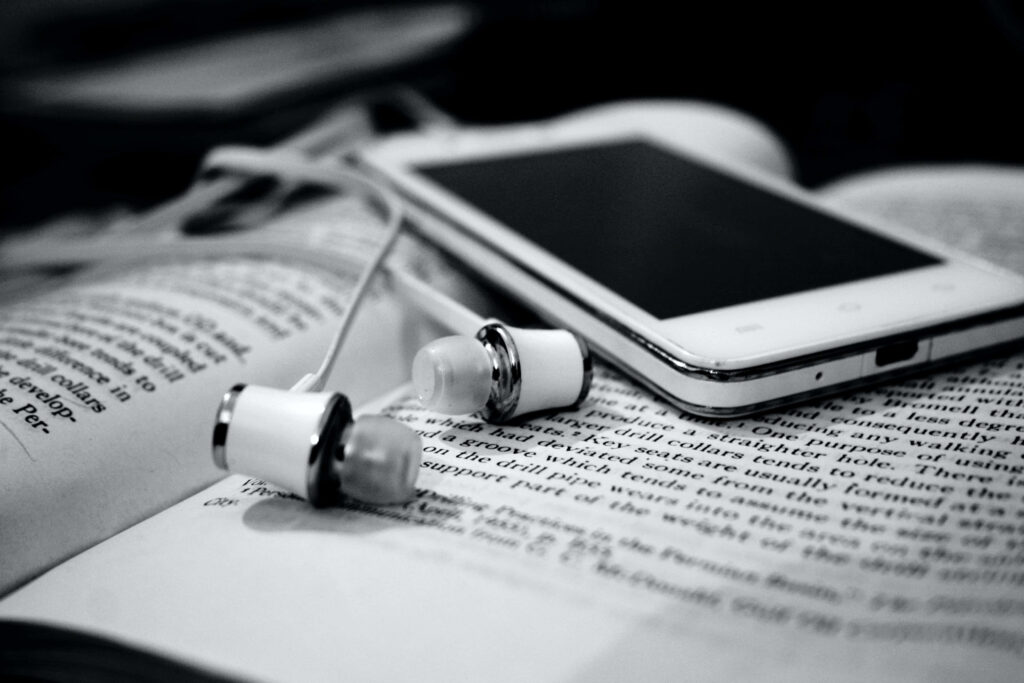 Monochrome Scene: Book, Smartphone & Earbuds on Wooden Surface Wallpaper