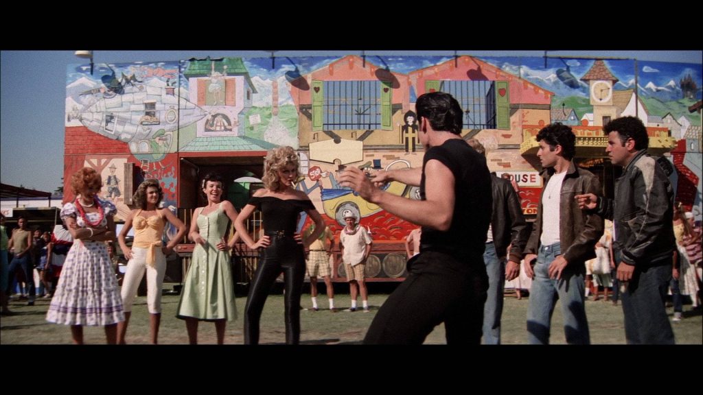 Grease 1978 movie still Danny Zuko and Sandy carnival backdrop iconic final looks wallpaper