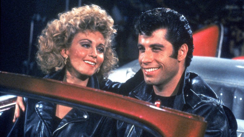 Grease wallpaper Danny and Sandy smiling in black leather jackets iconic movie romance