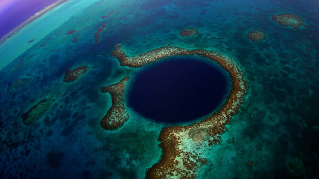 Aerial view of Great Blue Hole Belize surrounded by vibrant turquoise waters and coral reefs Wallpaper