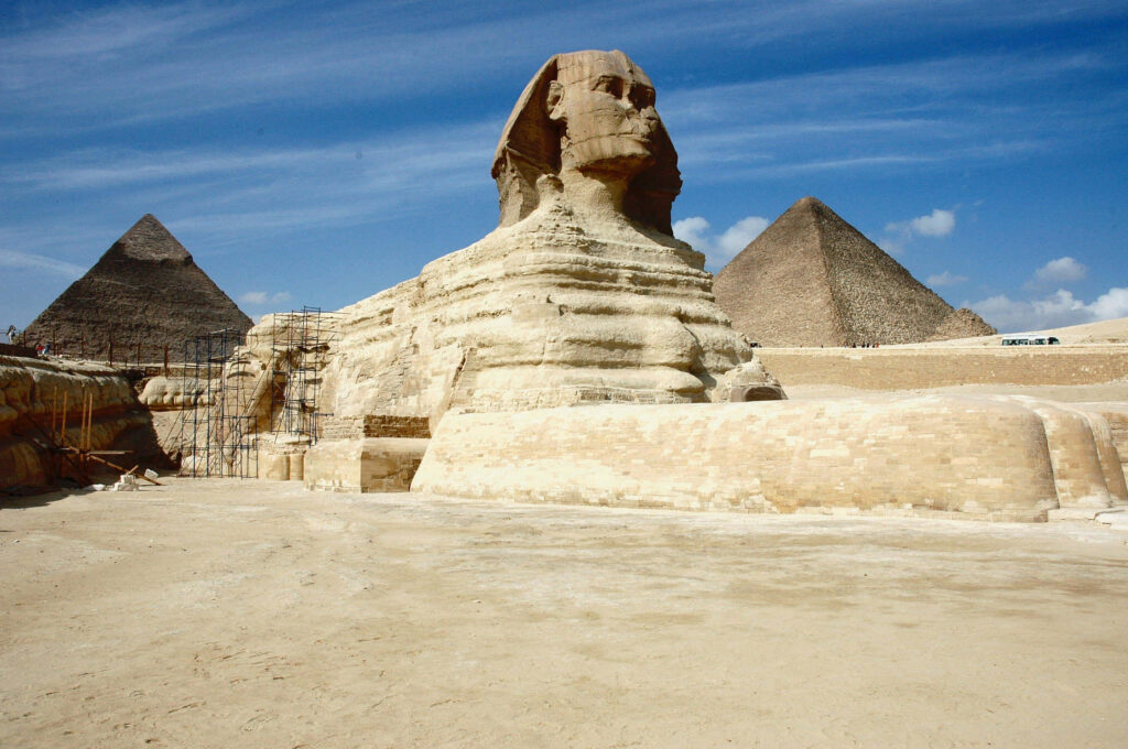 Great Sphinx and pyramids under clear blue sky showcasing ancient Egyptian stone architecture Wallpaper