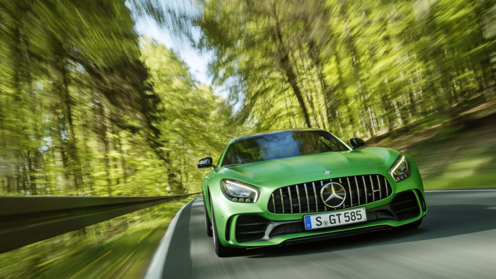 Green AMG GT R sports car speeding on forest road capturing power and precision motion blur Wallpaper