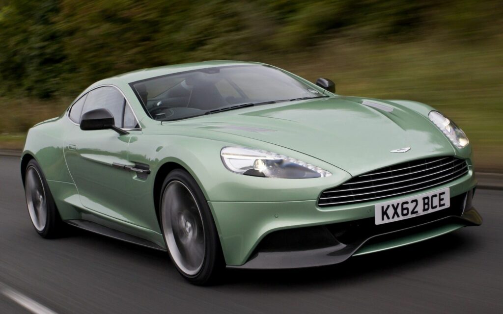 Sleek Green Aston Martin: Luxury Supercar Driving Scenic Road Wallpaper