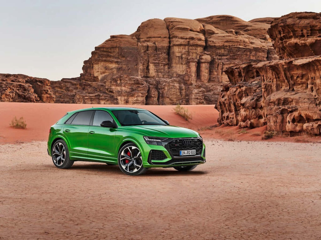 Green Audi RS Q8 SUV parked in rugged desert with rocky formations background wallpaper