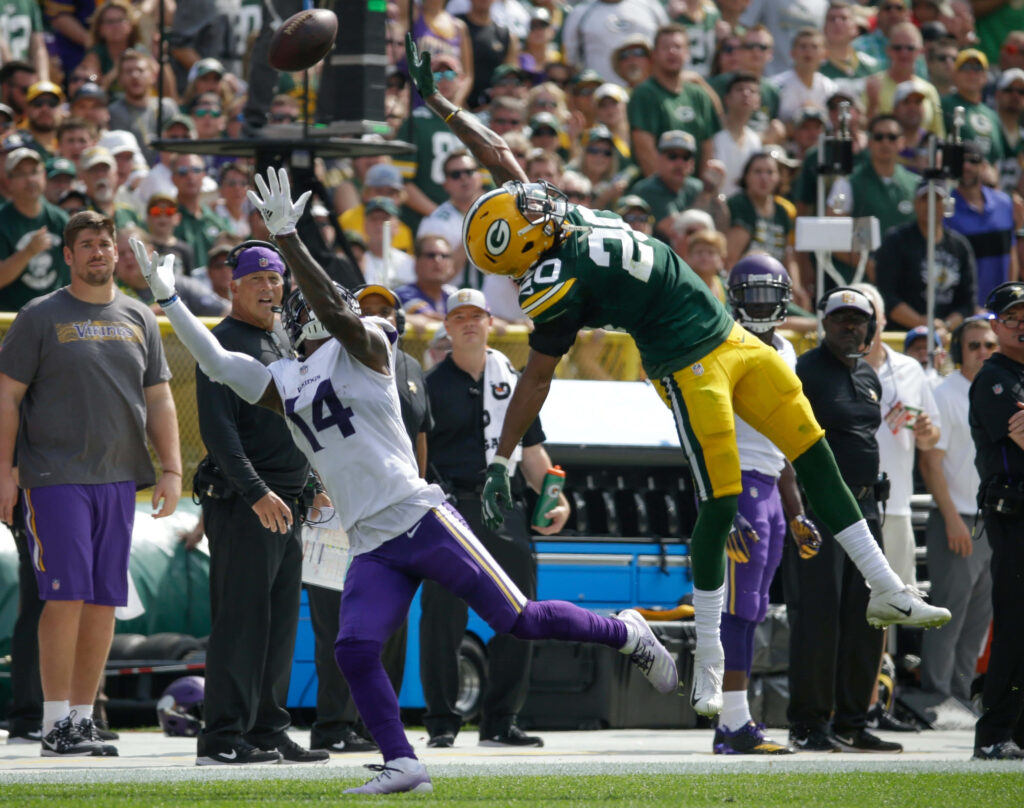 Green Bay Packers defender jumps to deflect pass from Minnesota Vikings receiver NFL game action Wallpaper