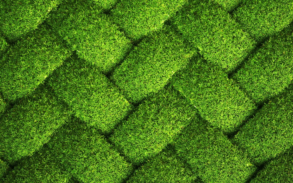 Vibrant QHD wallpaper of green woven grass texture with geometric synthetic turf tiles pattern