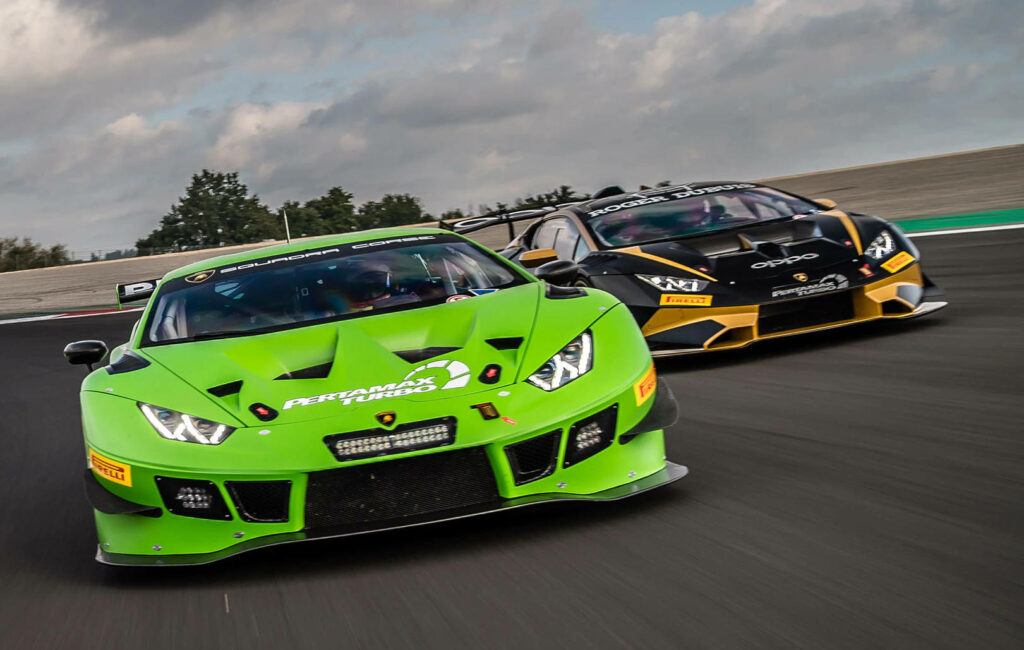Green Lamborghini Huracán leading motorsports race with another Lamborghini chasing on track Wallpaper