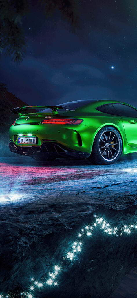 Green Mercedes AMG GT R parked on illuminated road at night with vibrant lights and starry sky Wallpaper