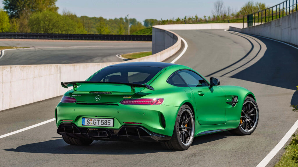 Green Mercedes AMG GT R rear view parked on smooth road with modern urban and green background Wallpaper