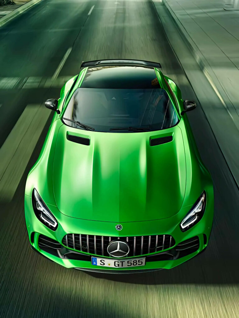 Green Mercedes-AMG speeding on road with sleek curves and dynamic performance wallpaper background