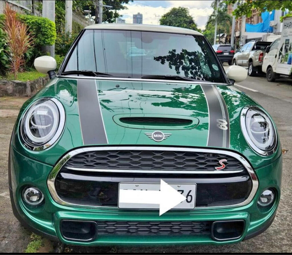 Front view of green Mini Cooper with black racing stripes on city street wallpaper background