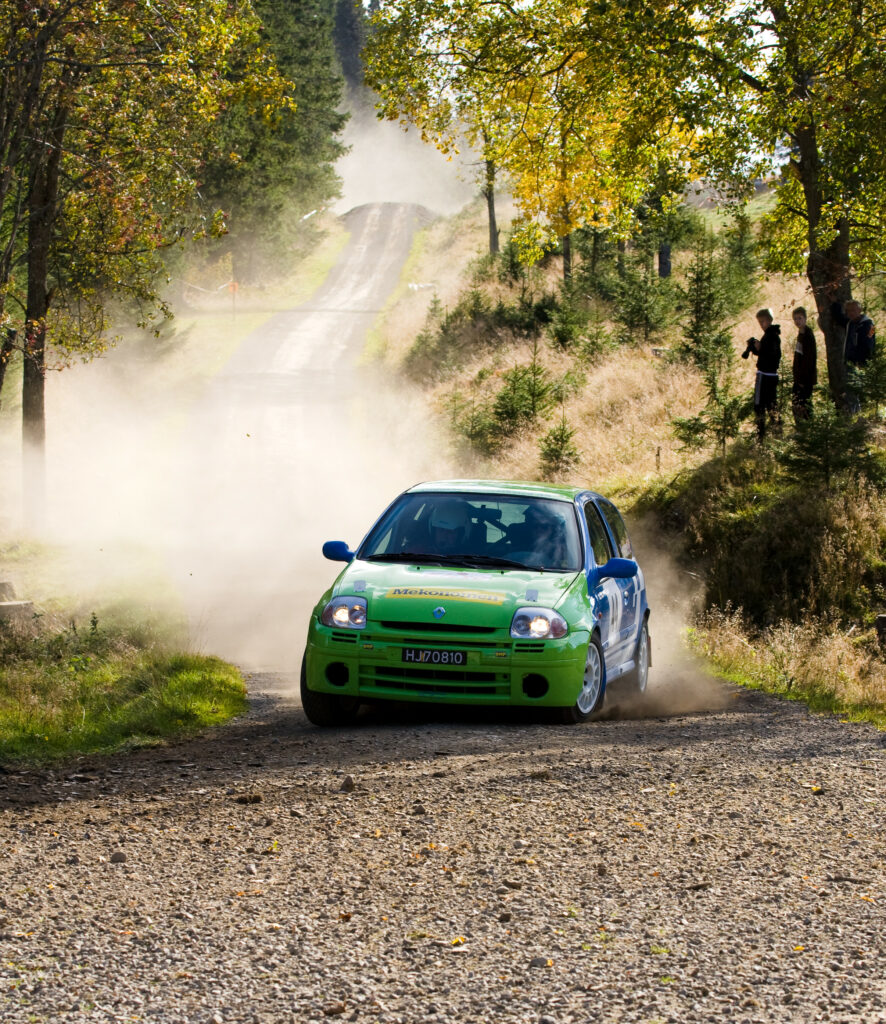 Green Renault Rally Car Racing on Dusty Rural Road - Dynamic Scene Wallpaper