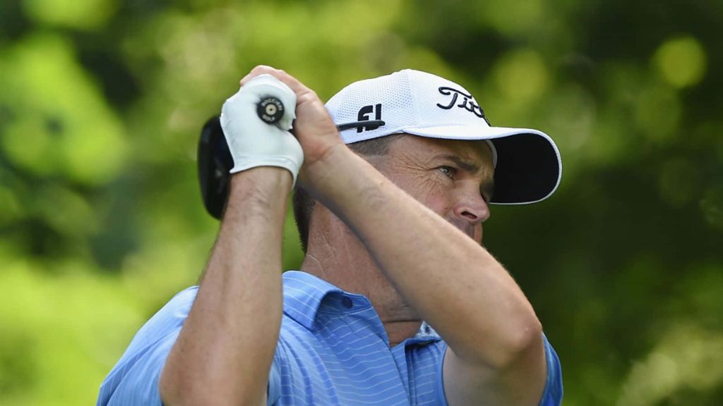 Professional golfer Greg Chalmers mid-swing wearing white Titleist cap and blue polo golf wallpaper