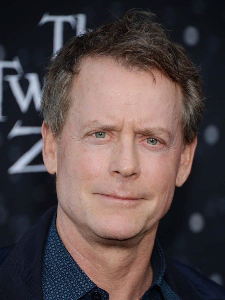 Close-up portrait of actor Greg Kinnear in dark patterned shirt and jacket with blurred background Wallpaper