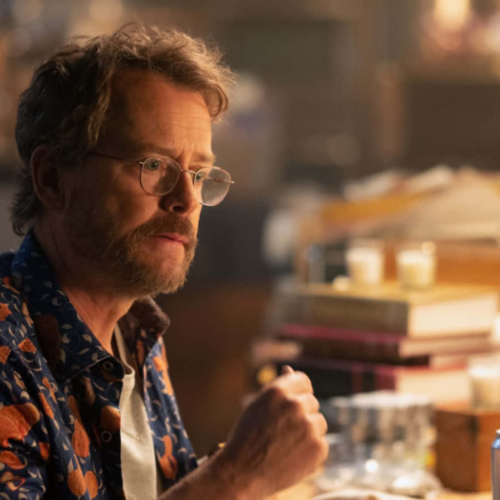 Greg Kinnear wearing glasses and orange shirt in a warm book-filled room thoughtful portrait Wallpaper