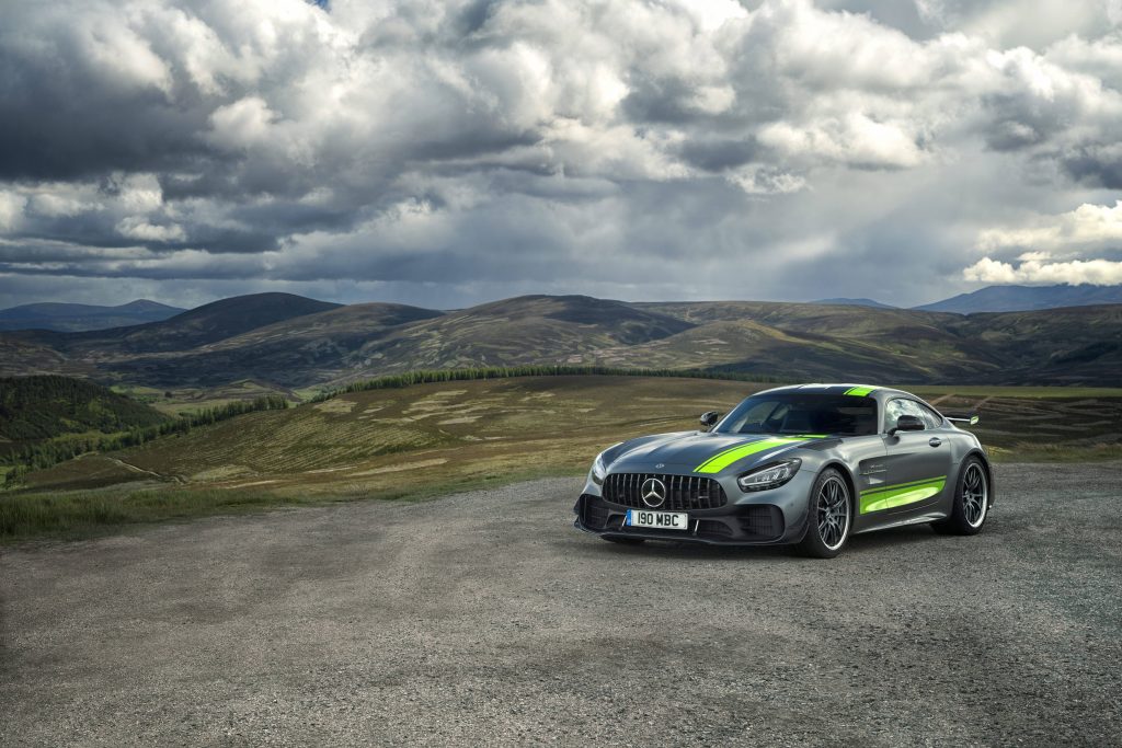 Grey Mercedes AMG GT R Pro on gravel road with green stripes highland cloudy landscape wallpaper