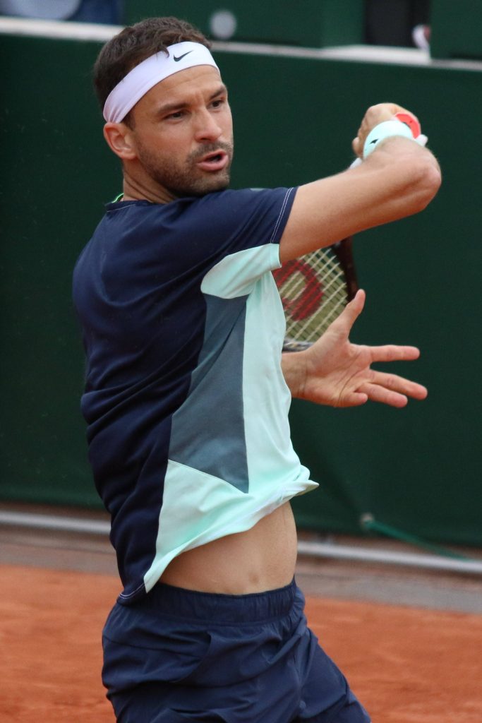 Grigor Dimitrov powerful tennis swing on red clay court in navy and light blue sportswear Wallpaper
