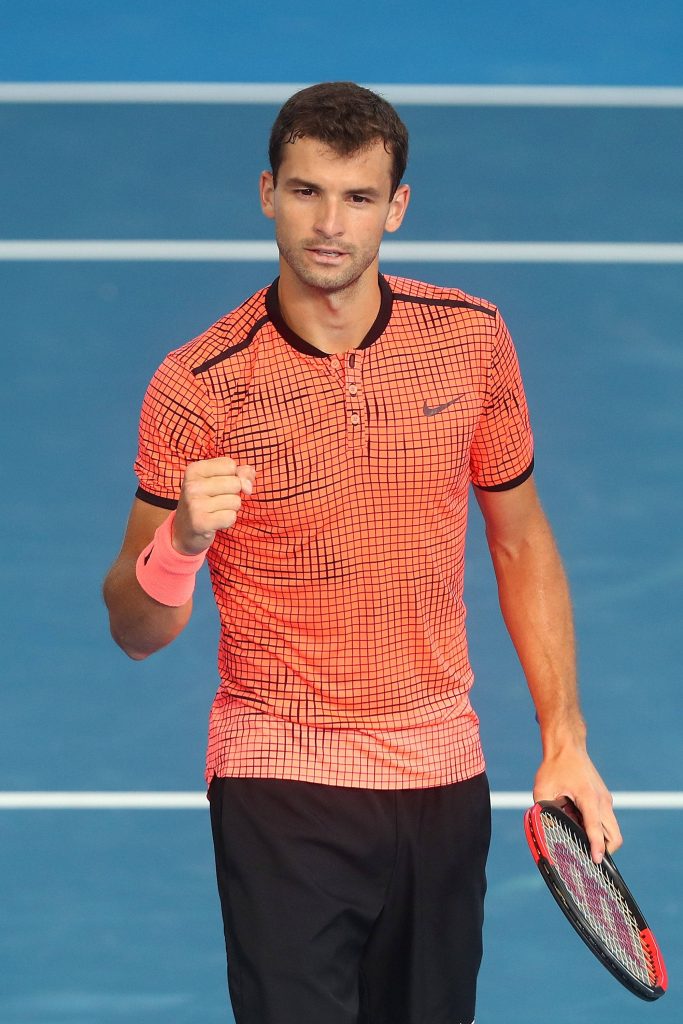 Grigor Dimitrov intense tennis action on blue court wearing orange Nike polo and pink wristband Wallpaper