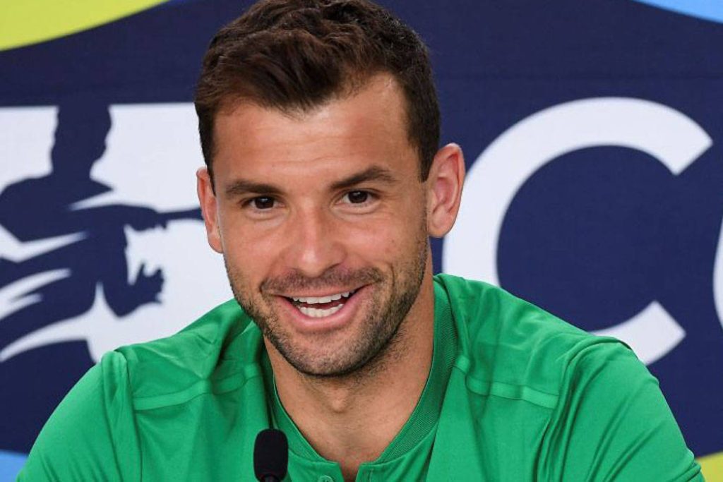 Grigor Dimitrov smiling in vibrant green shirt at press conference with colorful branded backdrop Wallpaper